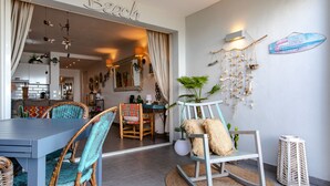 A dining area with wicker chairs, a round table, and a view into the kitchen. - Apartment on the beach (Grand-Case)