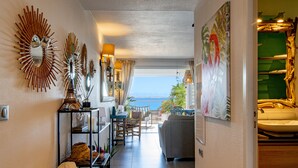 A hallway with a view of the sea, a sofa, a dining area, and various decorative items. - Apartment on the beach (Grand-Case)