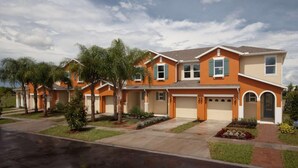 A row of two-story houses with attached garages, surrounded by well-maintained lawns and palm trees. - 5113 Compass Bay (Kissimmee)