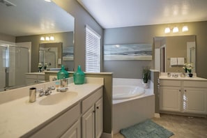 A modern bathroom with two sinks, a large bathtub, and a shower.