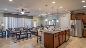 A spacious living area with a sofa, coffee table, and a kitchen island with a sink and refrigerator.