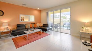 Una sala de estar moderna con sofá, mesa de centro y un amplio ventanal corredera que da a un patio exterior.