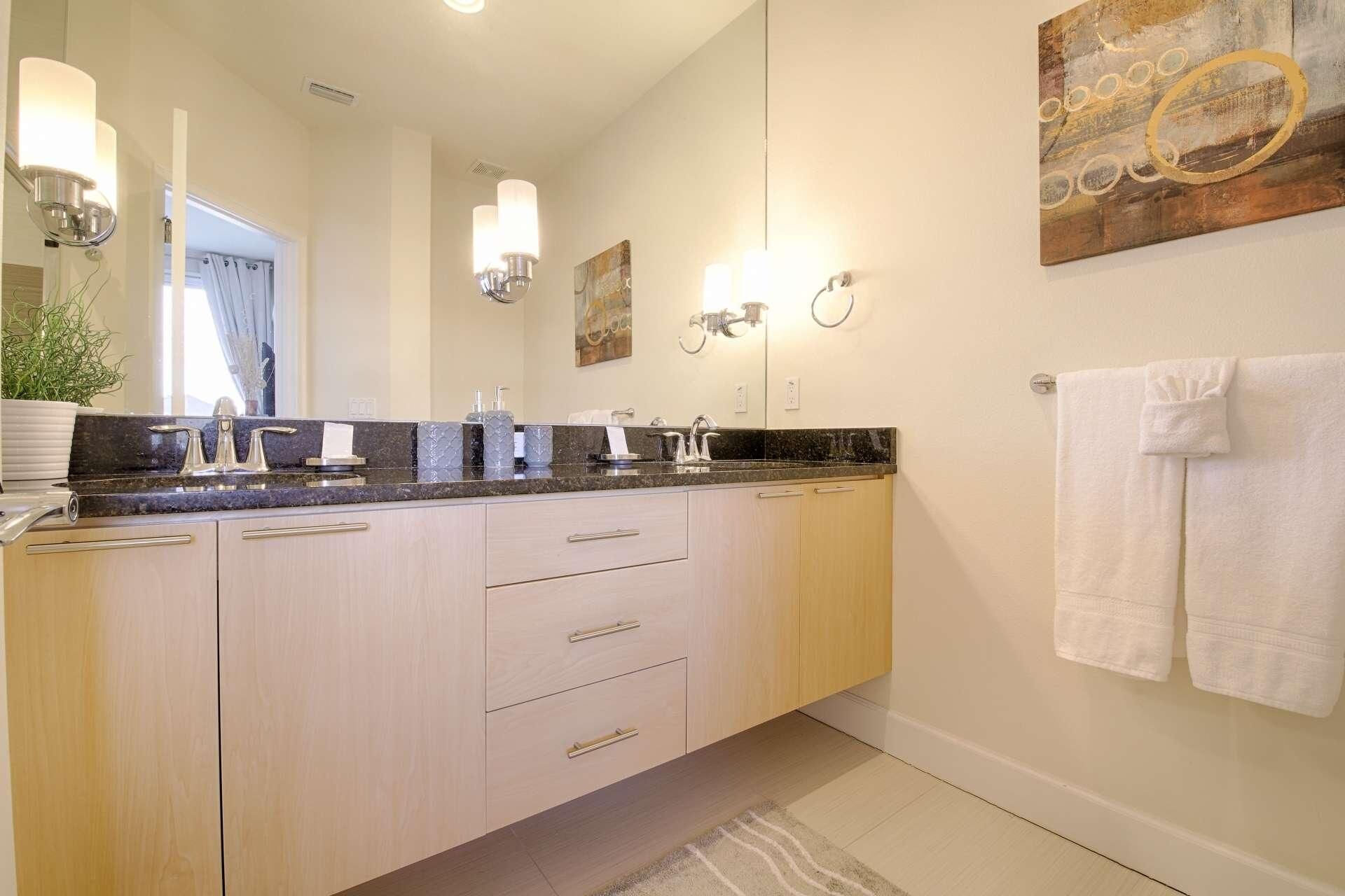 A modern bathroom with a large vanity, a mirror, and a towel rack.