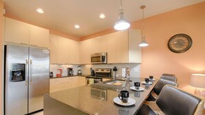 Una cocina moderna con electrodomésticos de acero inoxidable, una isla central con asientos y un comedor con sillas.
