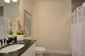 A bathroom with a sink, toilet, and shower curtain.