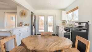 Una cocina moderna con armarios blancos, una mesa redonda de madera y una estufa negra.