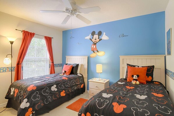 A bedroom with two beds, each with Mickey Mouse themed bedding, a ceiling fan, and a window with curtains. - 3153 Encantada (Kissimmee)