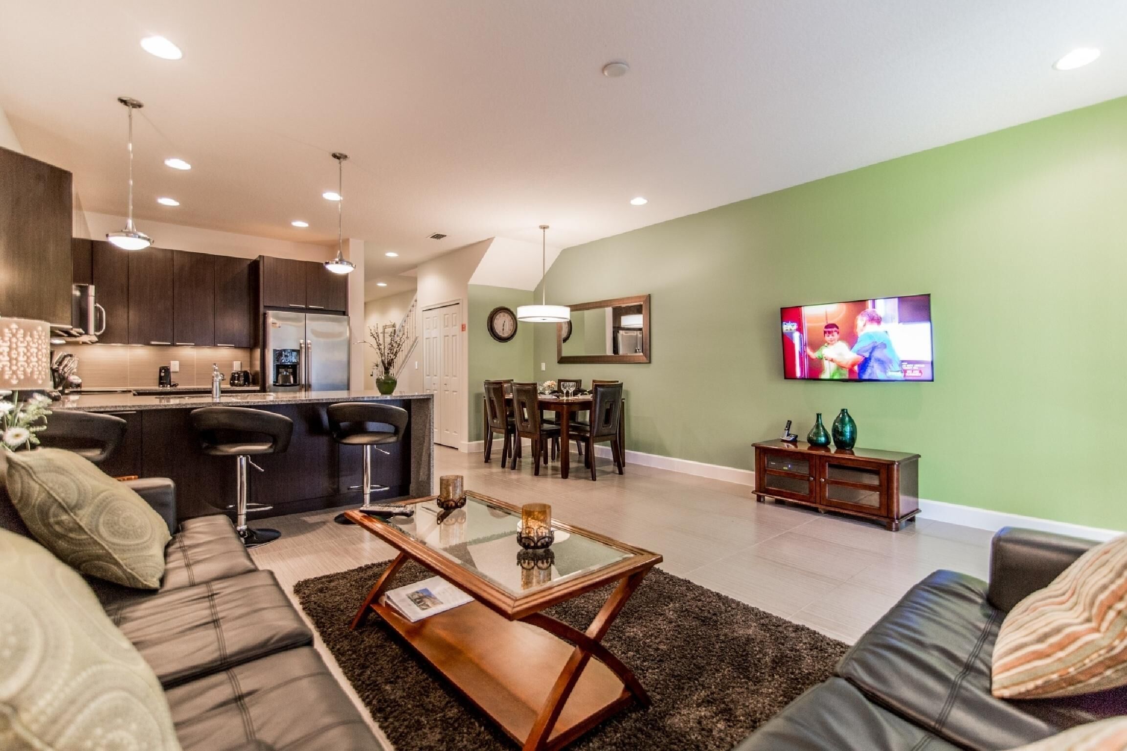 A modern living room with a sofa, coffee table, and a dining area with chairs and a table.