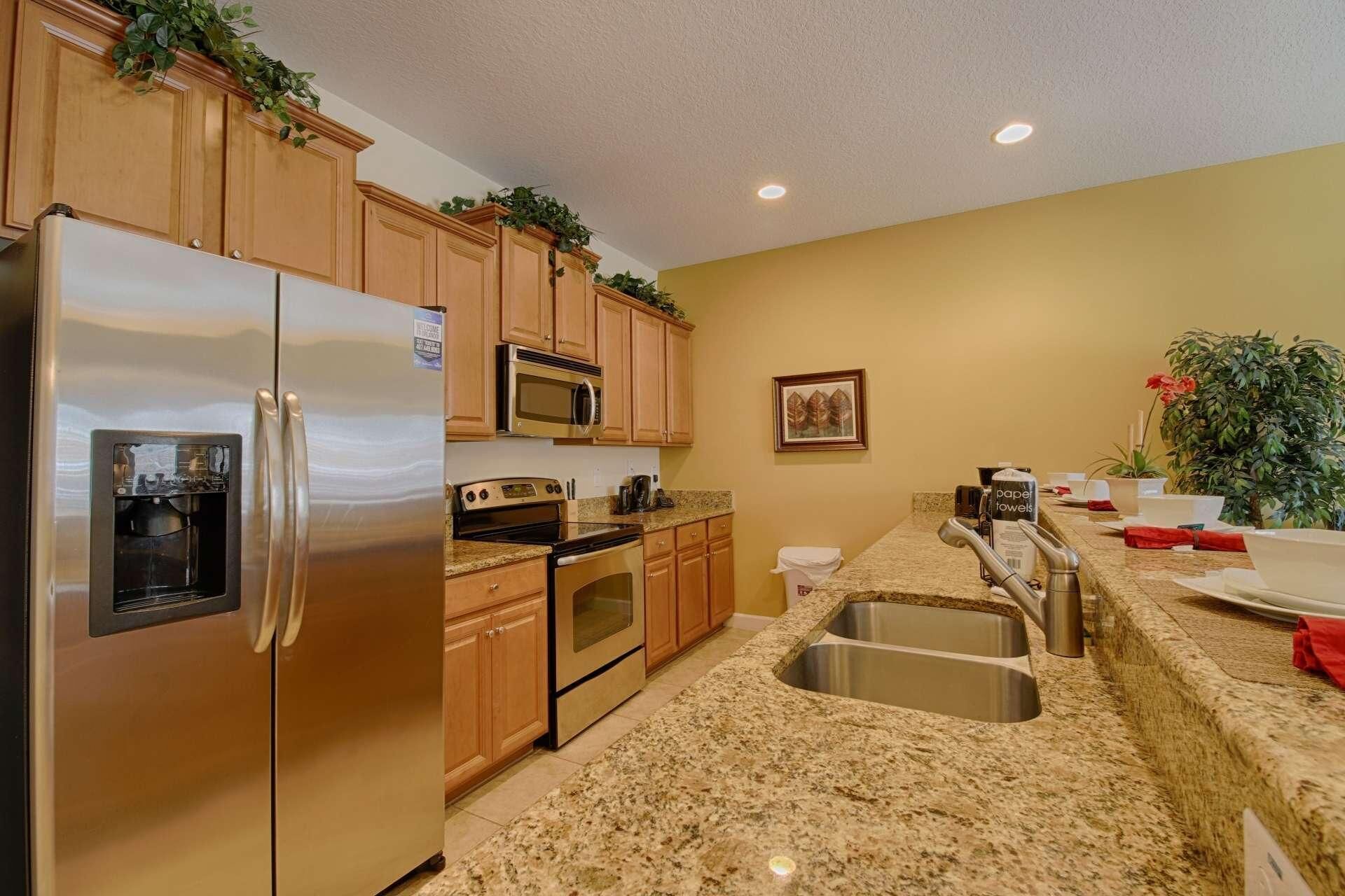 A kitchen with stainless steel appliances, wooden cabinets, granite countertops, and a sink.