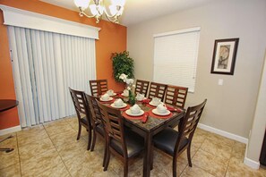 A dining area with a rectangular table set for six, surrounded by wooden chairs. - 8965 Paradise (Kissimmee)