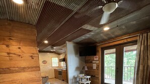 Uma sala de estar aconchegante com um sofá de couro, um tapete estampado e um ventilador de teto.