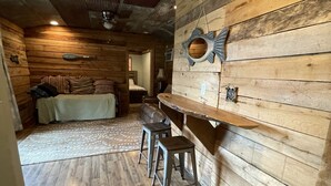 Interior rústico com paredes de madeira, área de jantar com banco e bancos, e teto com design em relevo.