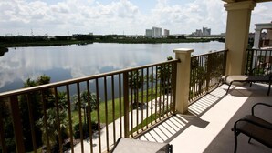 A balcony with a view of a calm lake, palm trees, and distant buildings. - Vista Cay 4804 (Orlando)