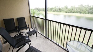 Een balkon met twee stoelen en een kleine tafel, met uitzicht op een rustig meer en groen.