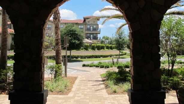 A stone archway leading to a landscaped area with a building in the background.