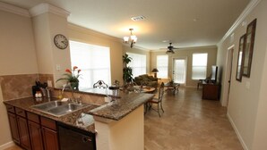 A spacious kitchen with granite countertops, a dishwasher, and a dining area with a table and chairs.