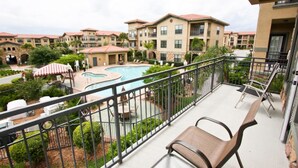 A balcony with a view of a swimming pool and surrounding buildings.