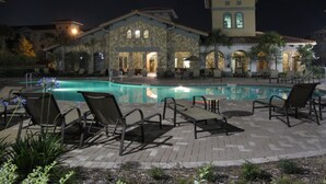 A poolside area with lounge chairs and a stone building with arched windows.