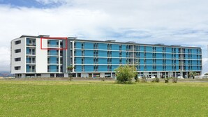 A modern multi-story hotel with a blue facade and white accents, featuring balconies and a flat roof.