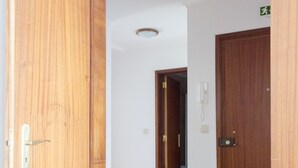 A hallway with wooden doors and a red chair.