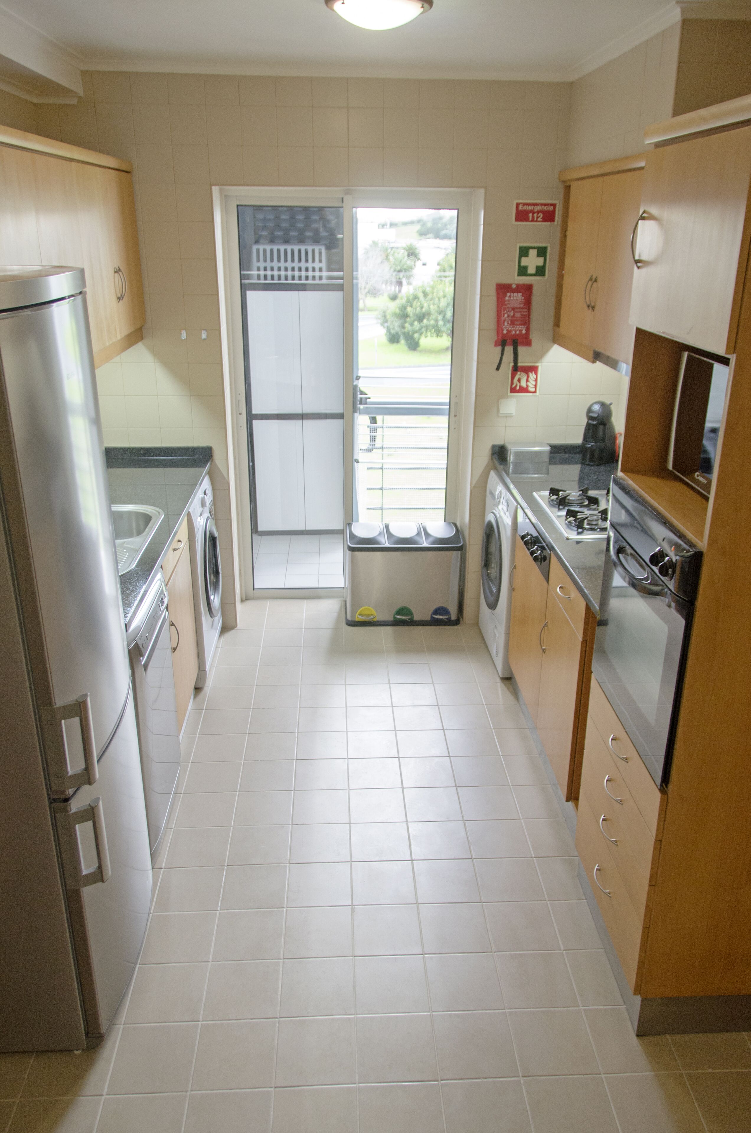 A compact kitchen with a washing machine, a refrigerator, a stove, and a sink.