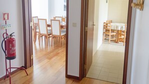 A hallway with wooden flooring leading to a dining area with chairs and a table.
