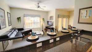 A modern kitchen with a dark granite countertop, a built-in sink, and a ceiling fan. - 8960 Paradise Palms (Kissimmee)
