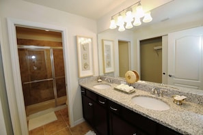 Une salle de bain avec deux lavabos, une douche et un grand miroir.