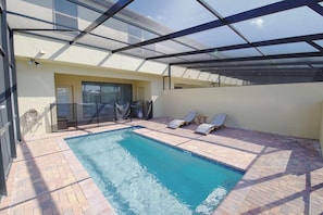 Une piscine avec des chaises longues et un espace patio couvert.
