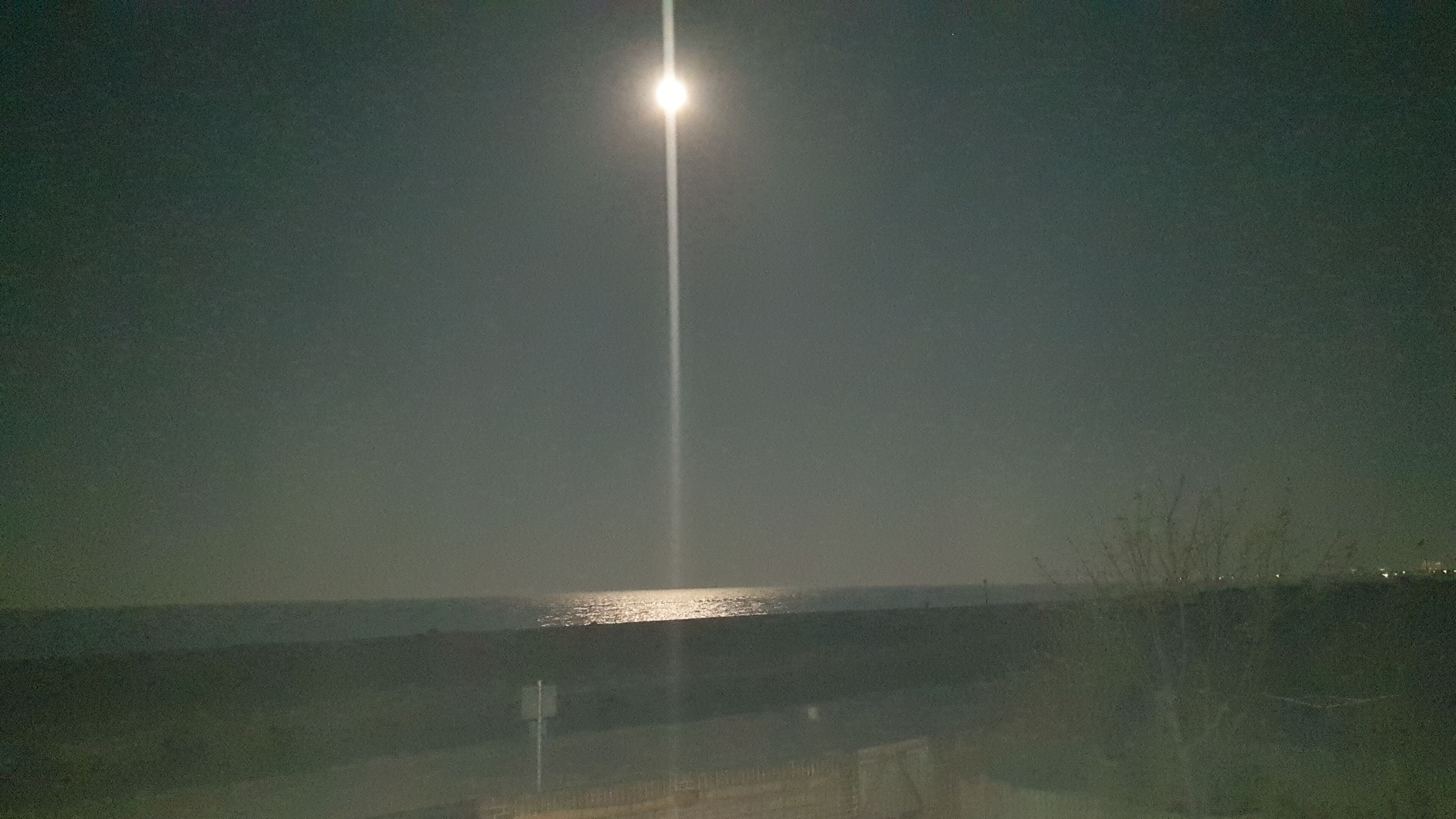 A streetlight with a clear view of the water and distant shoreline.
