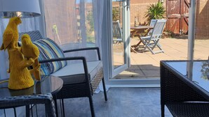 A patio area with wicker furniture, a glass table, and a yellow bird sculpture.