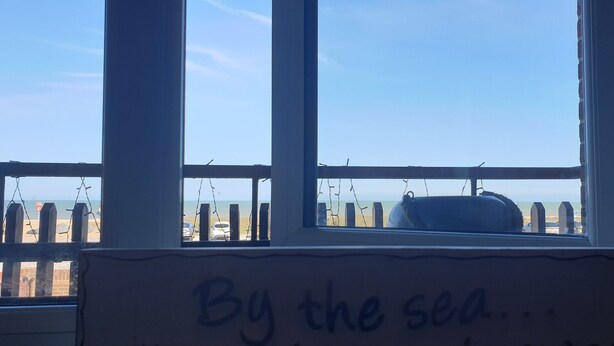 A view from a window with the text "By the sea..." visible.