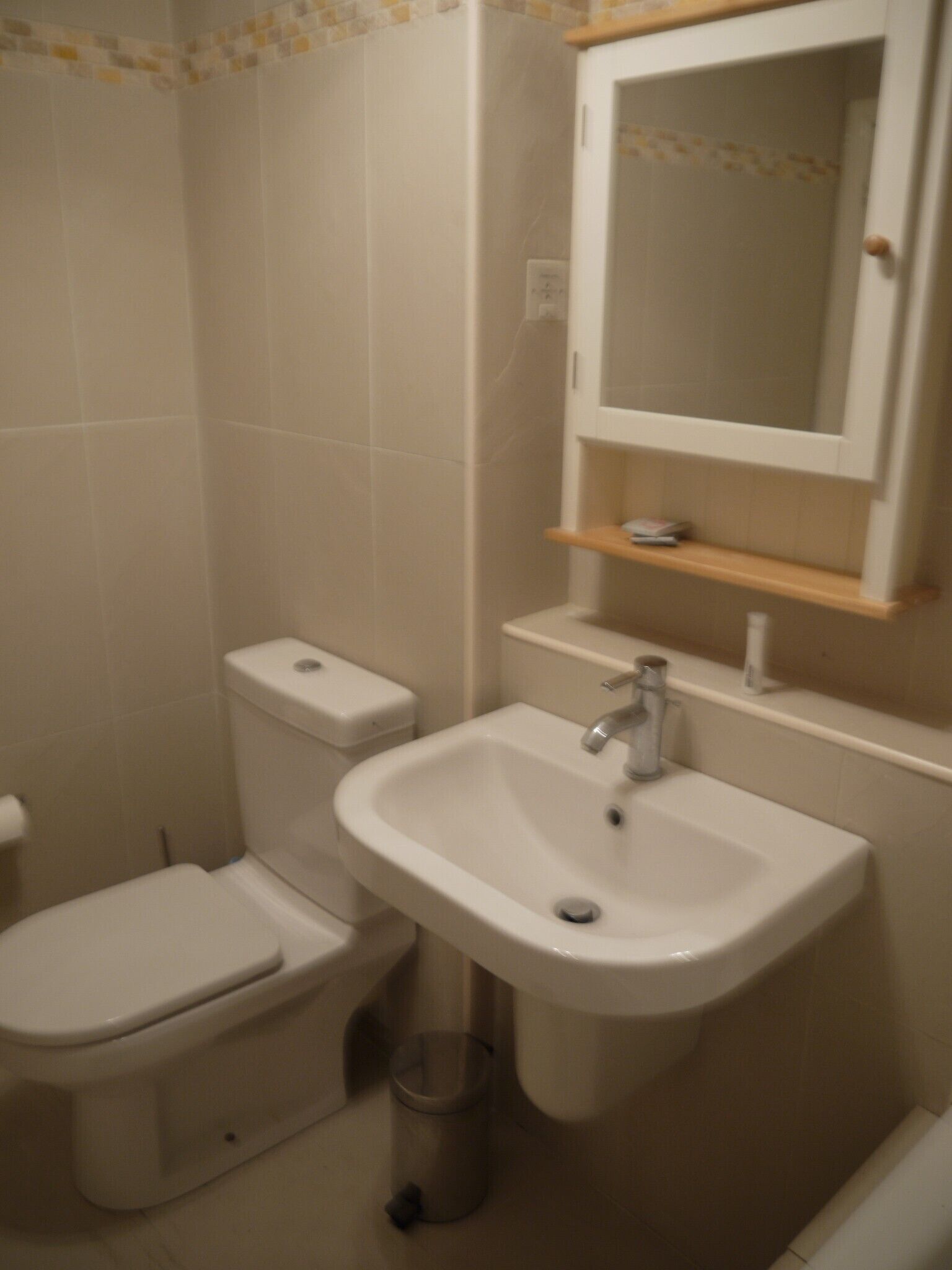 Un baño con inodoro, lavamanos y espejo.