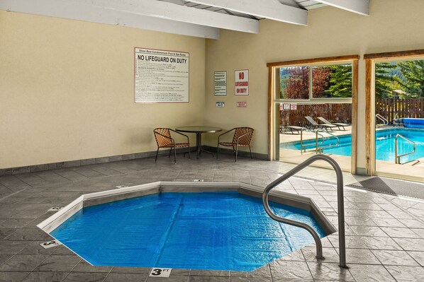 Un espace piscine avec un panneau indiquant la présence d’un sauveteur, une table de billard et des chaises longues.