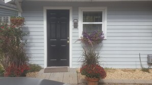 Uma casa com porta preta, uma pequena janela com moldura branca e uma caixa de correio com o número 1218.