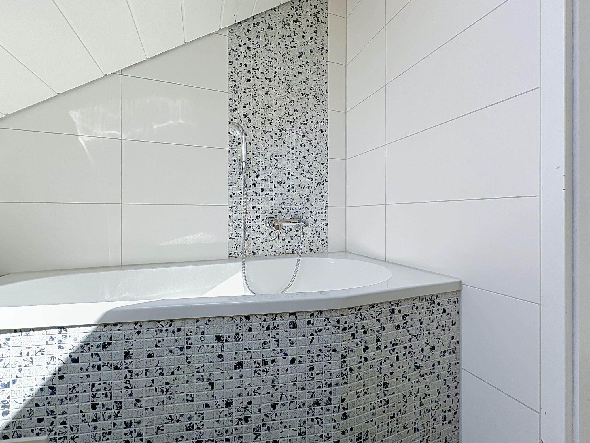 Ein modernes Badezimmer mit einer freistehenden Badewanne, gefliesten Wänden und einer Duschkabine.