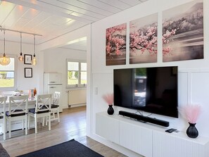 Ein modernes Wohnzimmer mit Flachbildfernseher, weißen Schränken und Kunstwerken darüber.