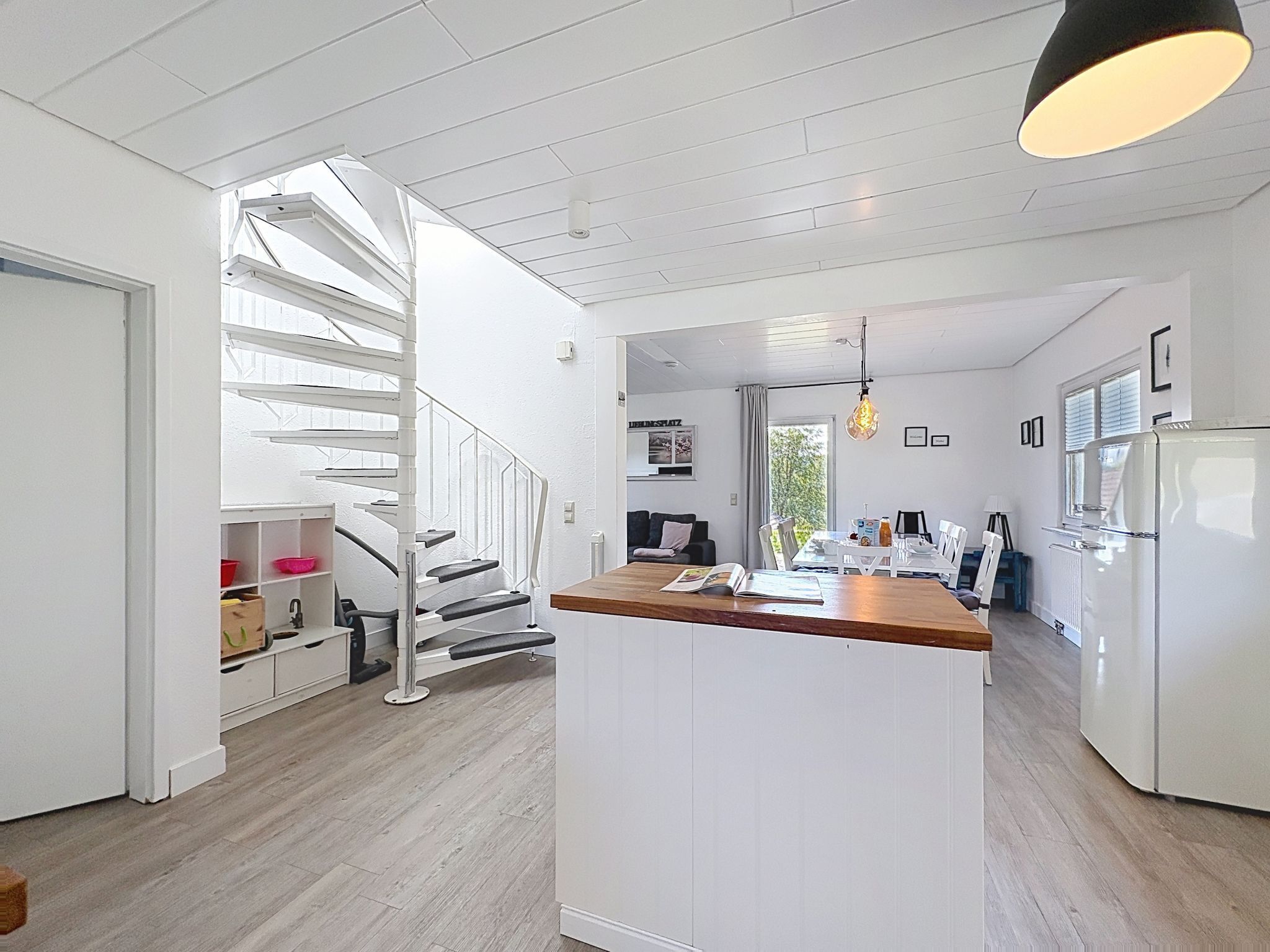 Une cuisine moderne dotée d’un îlot central, de meubles blancs et d’un escalier menant à un autre niveau.