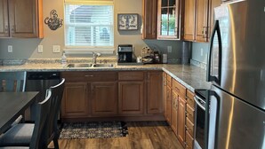 A modern kitchen with wooden cabinets, stainless steel appliances, and a dining area with a table and chairs.