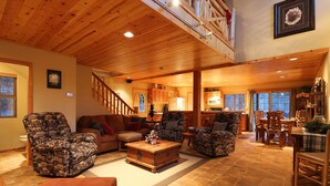 A spacious living room with a high ceiling, wooden flooring, and a cozy fireplace. - Walk 2 Ski/Hiking/Biking Trails w/Spa/Pool Table/Sauna/Fenced Yard, Pet Friendly (Big Bear Lake)