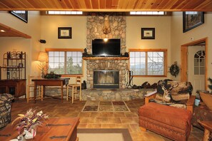 A cozy living room with a stone fireplace, a television, and comfortable seating.