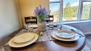 Et spisebord dækket med tallerkener, bestik, glas og en vase med blomster.