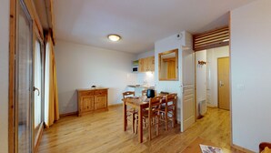 Une cuisine de taille réduite avec des meubles en bois, une table à manger avec des chaises et un four à micro-ondes.