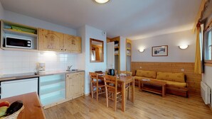 Une cuisine compacte avec des meubles en bois, un four à micro-ondes et un coin repas comprenant une table et des chaises en bois.