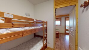 Une chambre avec des lits superposés, sur laquelle est affiché un panneau indiquant qu’il est prévu quatre serviettes par lit.