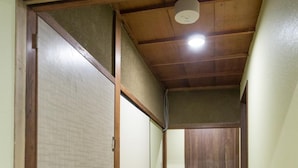A narrow hallway with wooden flooring and a wooden door at the end. - Woodon - Hostel (Osaka)