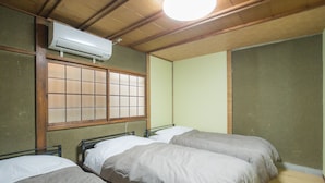 A room with two beds, a window with wooden frames, and an air conditioning unit on the ceiling. - Woodon - Hostel (Osaka)