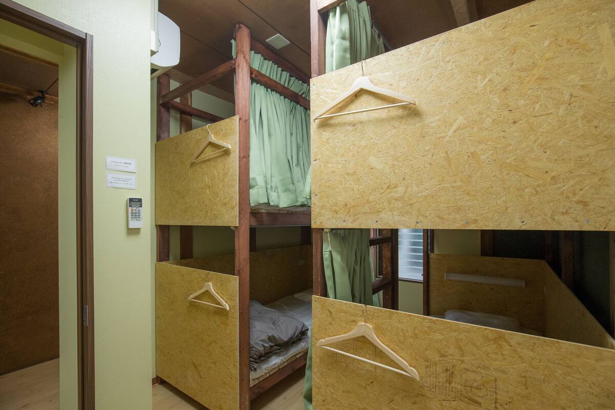A dormitory room with bunk beds, wooden bunk beds, and a wooden door.