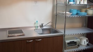 A compact kitchenette with a stainless steel sink, a digital scale, a kettle, and a microwave. - Woodon - Hostel (Osaka)