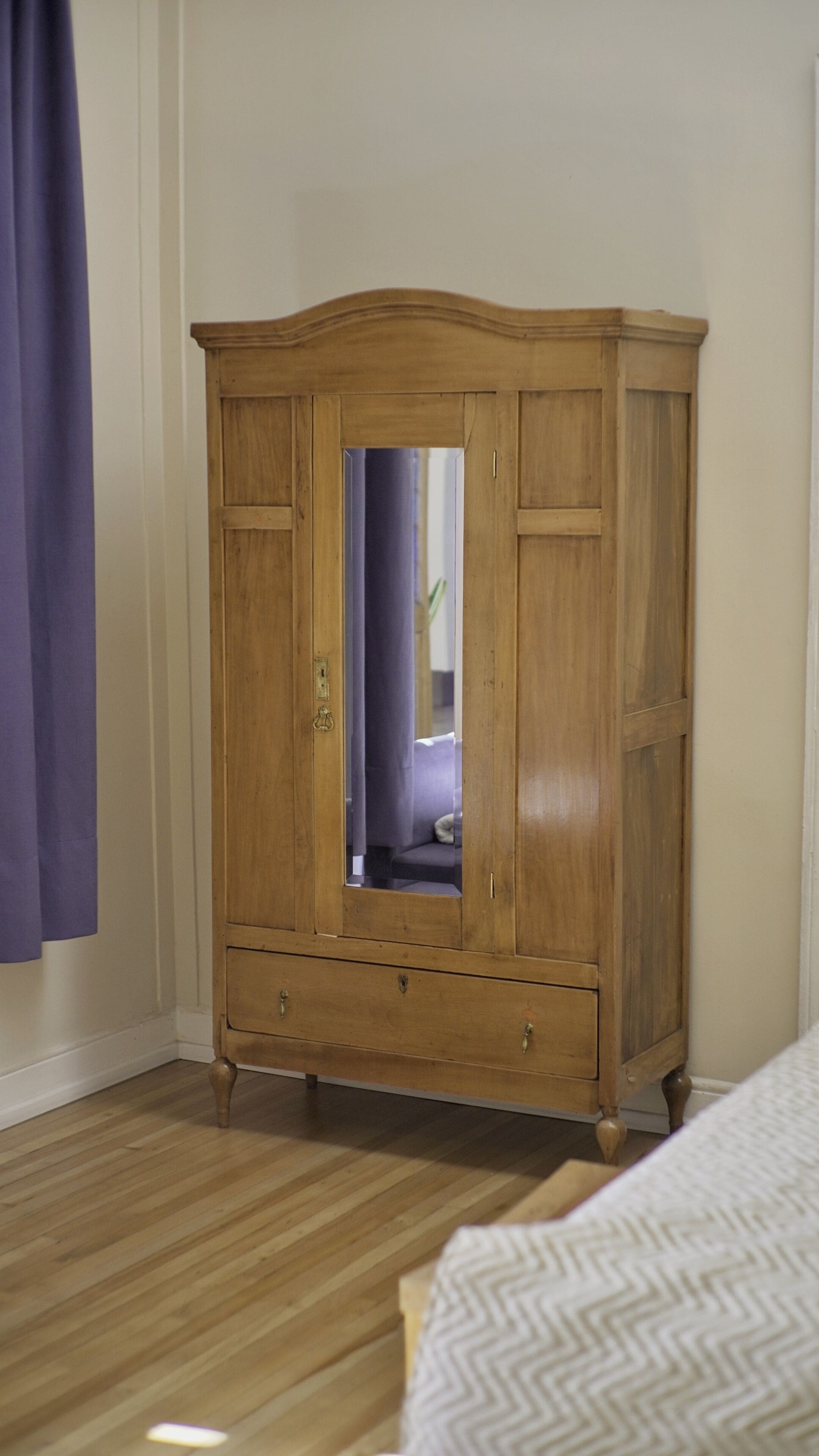 Une armoire en bois avec un miroir, des tiroirs et une petite étagère.